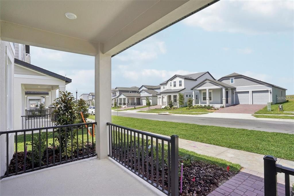 A view from a covered porch looking out at a suburban street with neighboring houses — 16484 SILVER BROOK WAY, WINTER GARDEN, FL