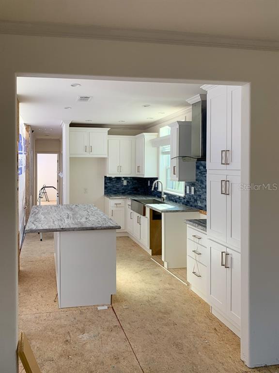 A kitchen under construction features white cabinets, a marble-patterned island, and blue tile backsplash — 71 TWIN SHORES BOULEVARD, LONGBOAT KEY, FL