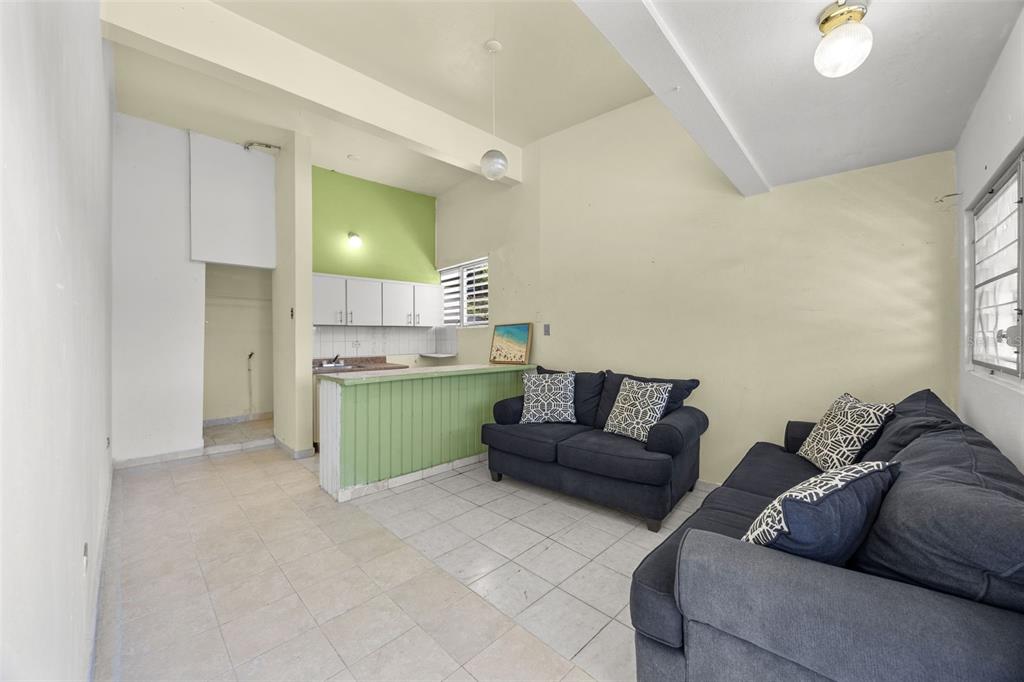 A living room with tile floors, a small kitchen area, and two dark sofas — 303 Calle El Salto EL SALTO, ANASCO, PR