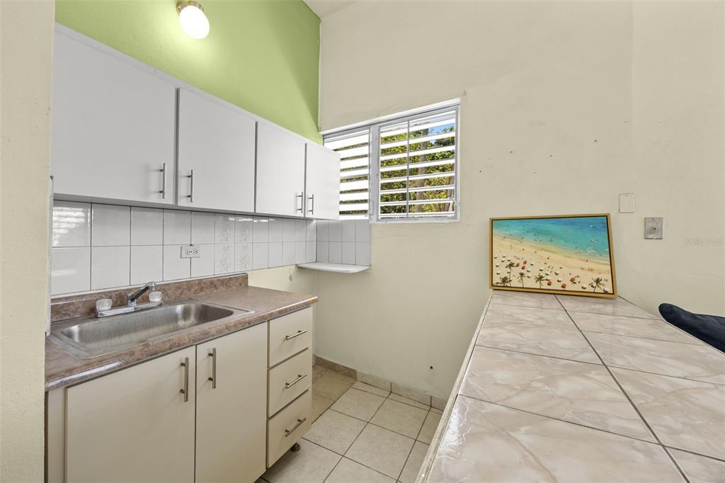 A kitchen features white cabinets, a stainless steel sink, tiled countertops, and a window — 303 Calle El Salto EL SALTO, ANASCO, PR