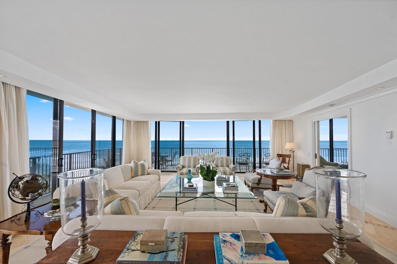 A bright living room features white sofas, a glass coffee table, and floor-to-ceiling ocean views — 150 N Ocean Boulevard # 3, Palm Beach FL 33480, PALM BEACH, FL