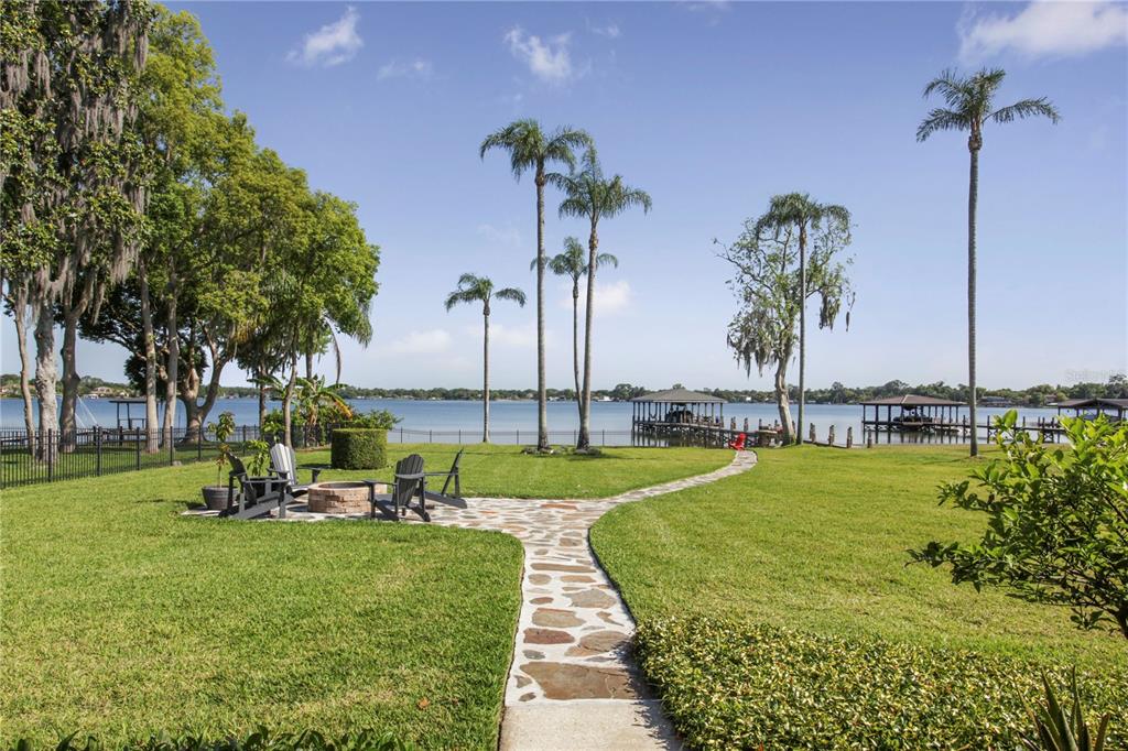 A stone path leads across a grassy lawn toward a lake with two boat docks — 6007 LINNEAL BEACH DRIVE, APOPKA, FL