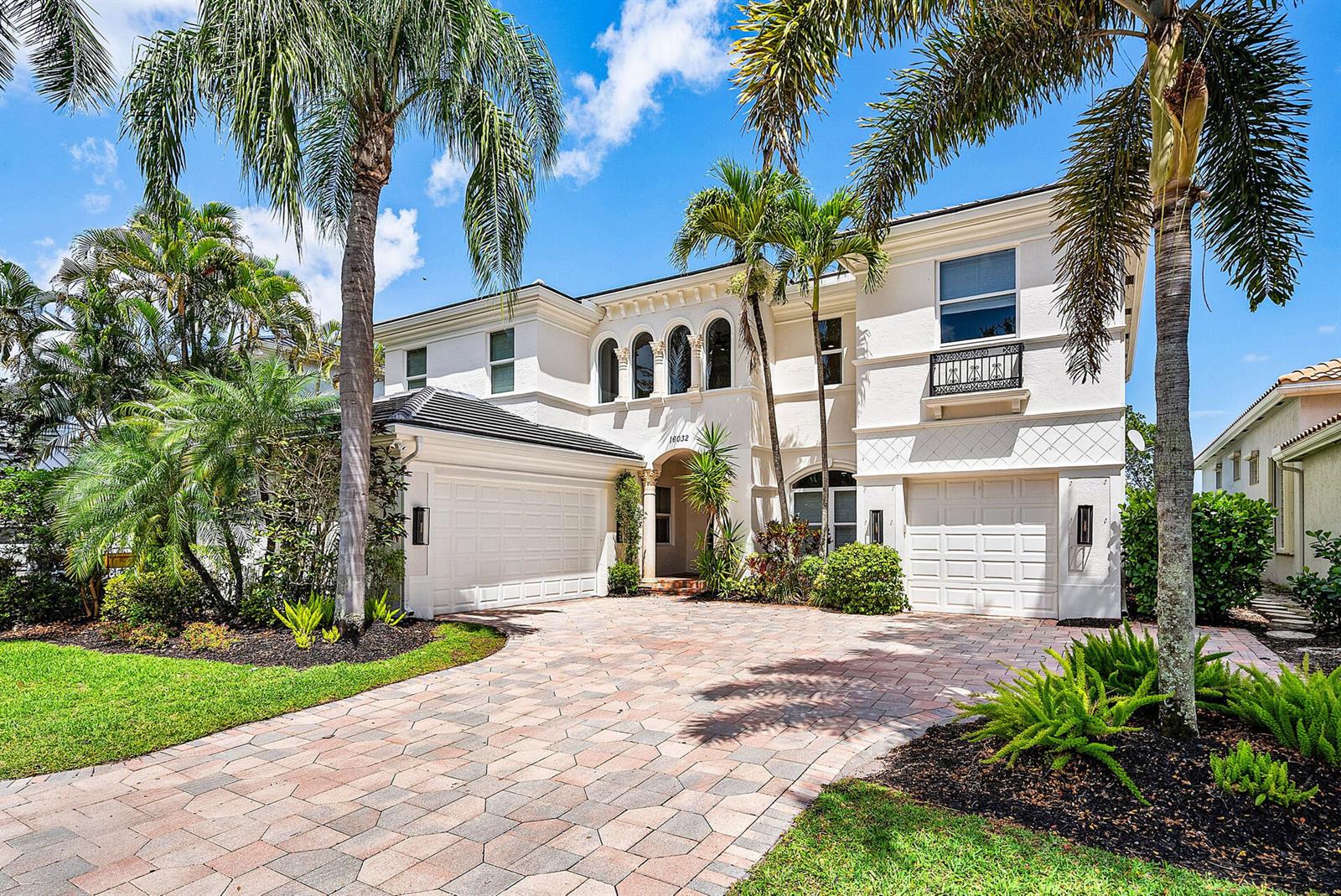 A two-story white stucco house features a paved driveway, arched windows, and palm trees — 16032 Bristol Isle Way, Delray Beach FL 33446, DELRAY BEACH, FL