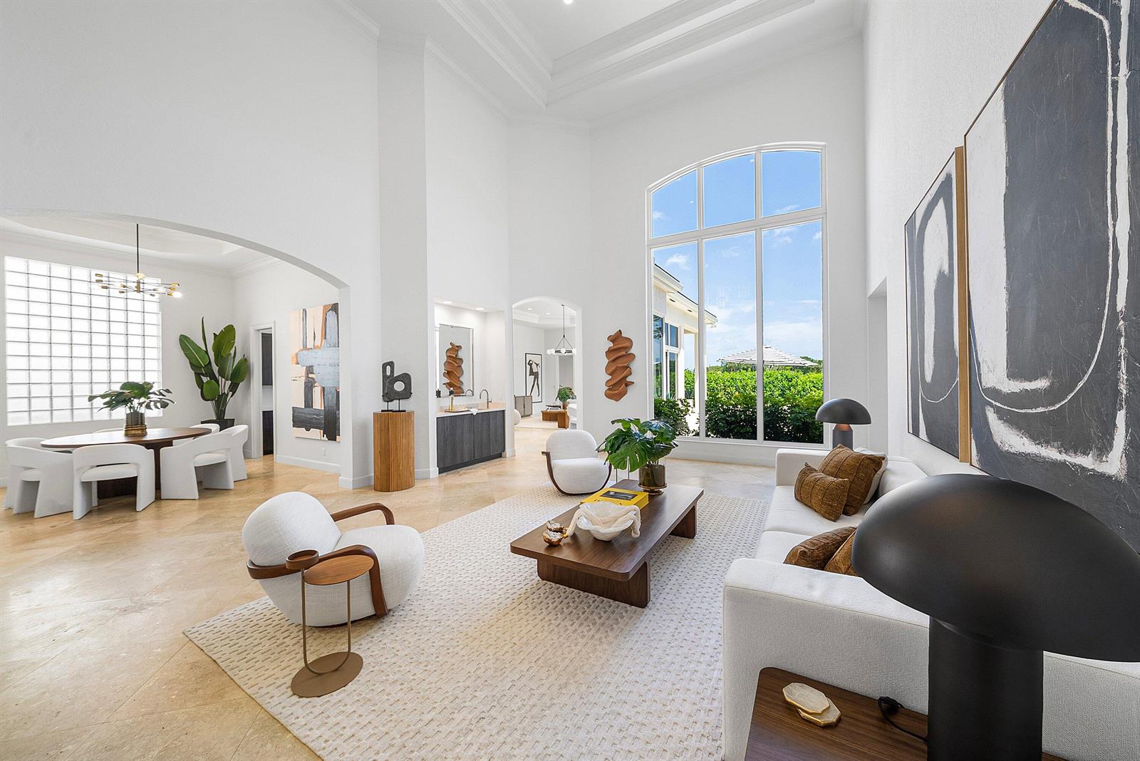 A spacious, high-ceilinged living room features white walls, a large arched window, and modern furniture — 16032 Bristol Isle Way, Delray Beach FL 33446, DELRAY BEACH, FL