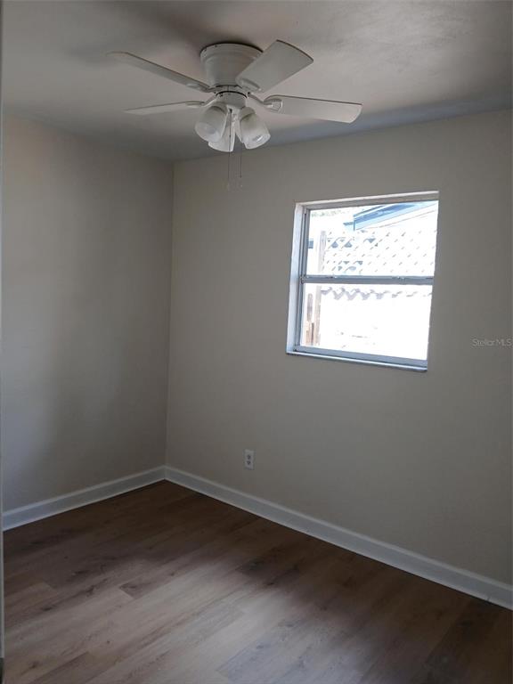A living room with light yellow walls, wood-look flooring, a ceiling fan, and built-in shelving — 2834 25TH AVENUE N, ST PETERSBURG, FL