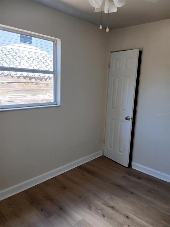 A room with light yellow walls, wood-look flooring, a ceiling fan, and two windows — 2834 25TH AVENUE N, ST PETERSBURG, FL