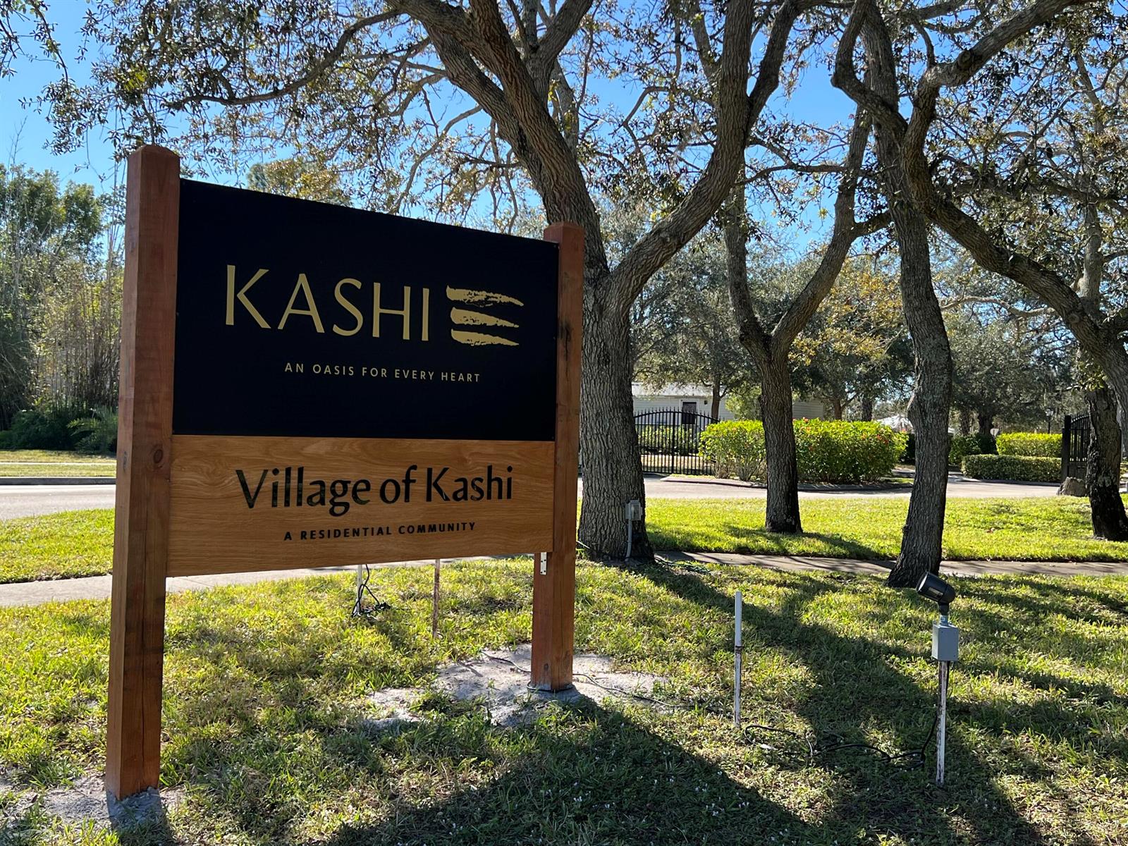 A wooden sign for the Village of Kashi residential community stands on a grassy lawn — 11324 Ganesh Way, Sebastian FL 32958, SEBASTIAN, FL