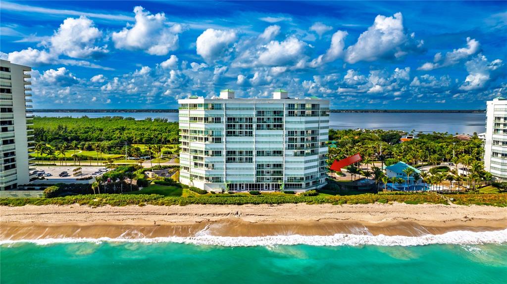 An aerial view shows a multi-story beachfront condominium building with a red arrow pointing right — 8650 S OCEAN DR UNIT 301, JENSEN BEACH, FL