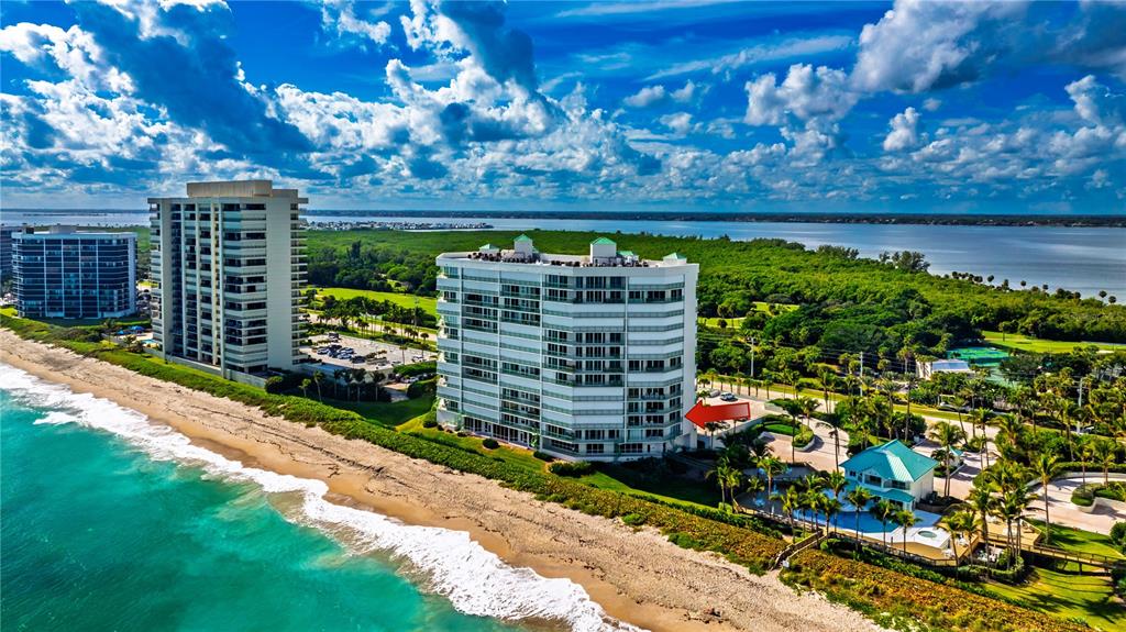 An aerial view shows two high-rise residential buildings situated along a sandy beach — 8650 S OCEAN DR UNIT 301, JENSEN BEACH, FL