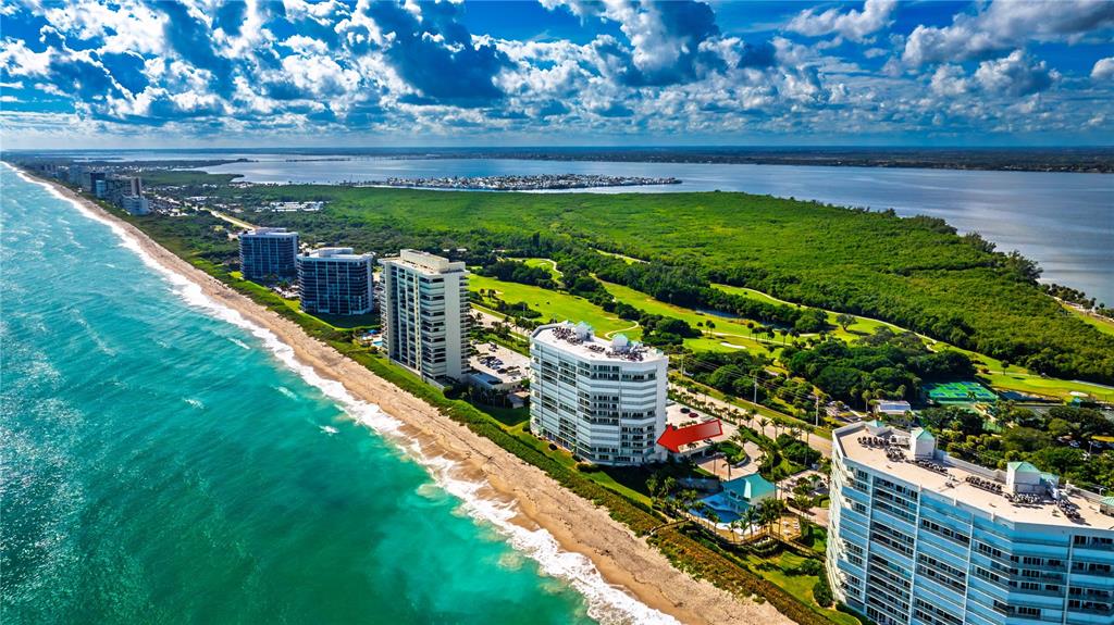 Aerial view of high-rise beachfront condominiums situated along a coastline next to a golf course — 8650 S OCEAN DR UNIT 301, JENSEN BEACH, FL