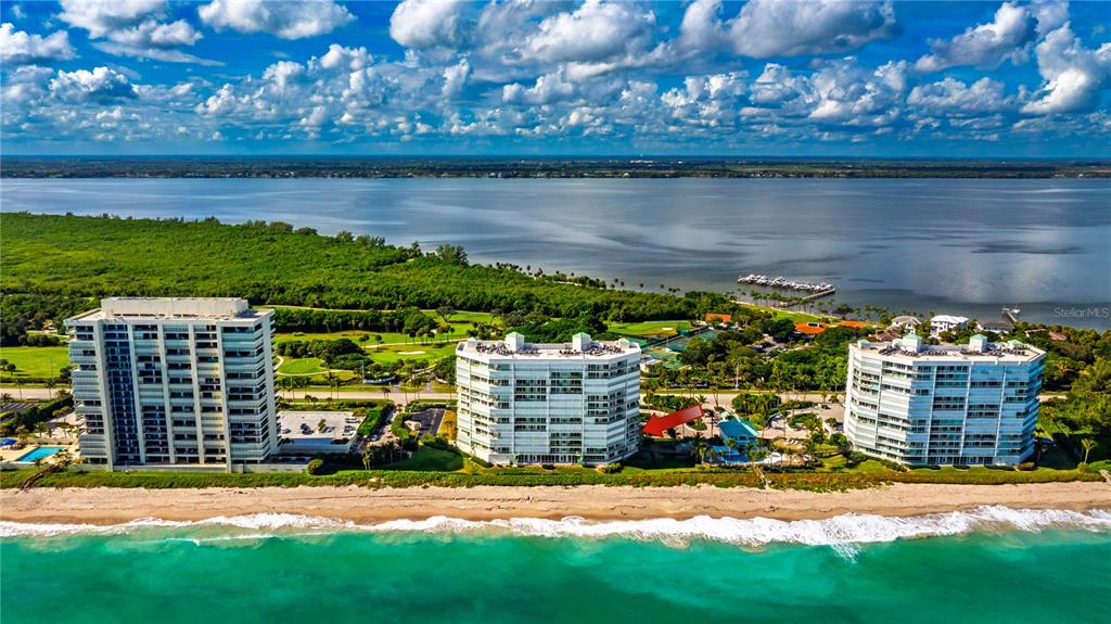 An aerial view shows three beachfront condominium buildings along a coastline with a large bay — 8650 S OCEAN DR UNIT 301, JENSEN BEACH, FL