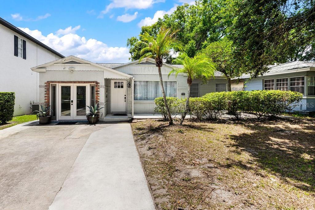 A single-story house with a white exterior, a concrete driveway, and two small palm trees — 1518 E JEFFERSON STREET, ORLANDO, FL