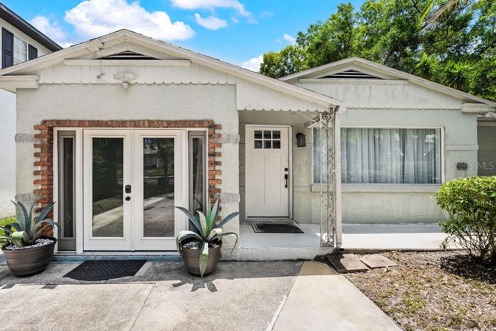 The exterior of a single-story house features a white door, double glass doors, and landscaping — 1518 E JEFFERSON STREET, ORLANDO, FL