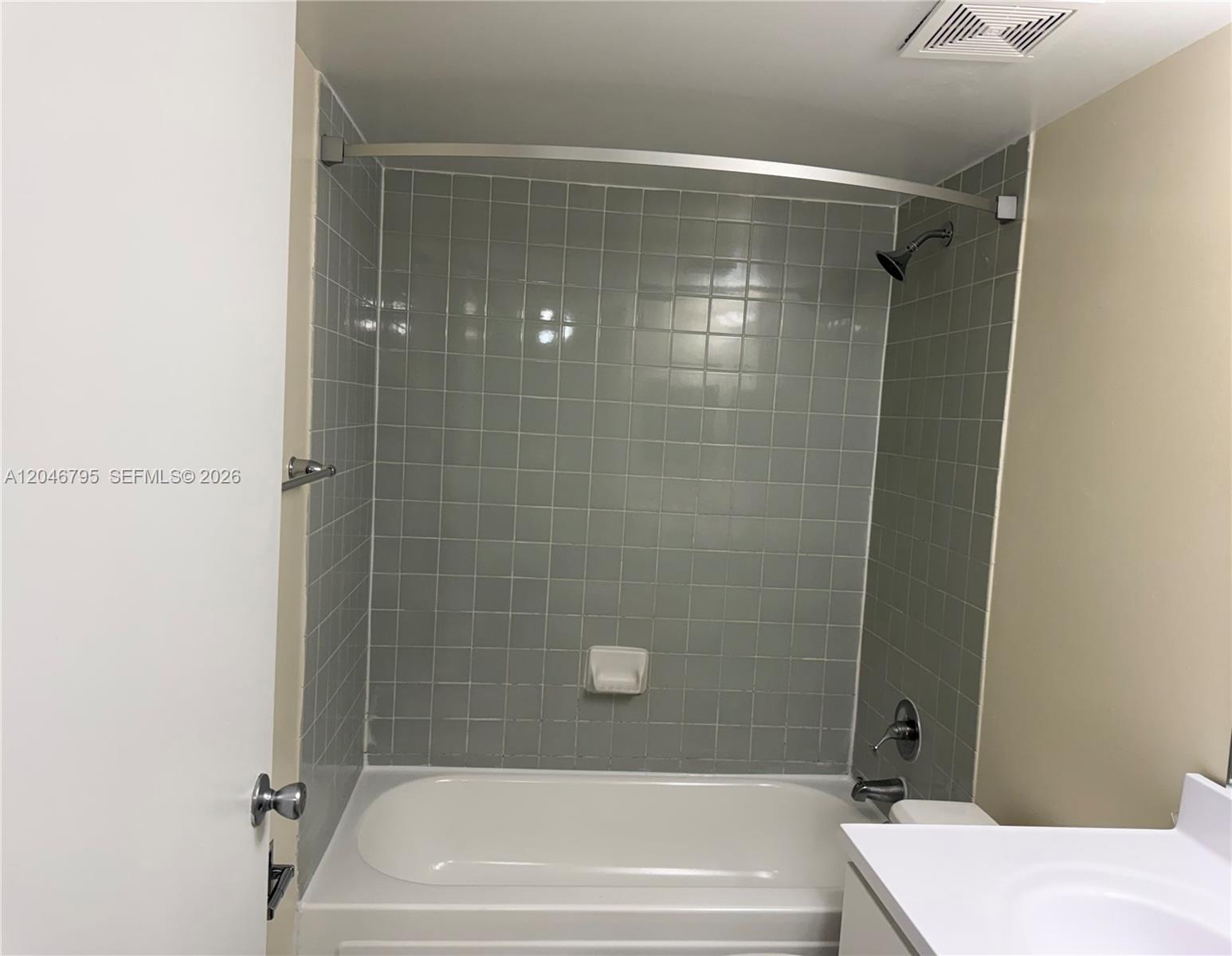 A bathroom features a white bathtub, gray tiled walls, and a curved shower rod — 915 NW 1st Ave, Miami FL 33136, MIAMI, FL