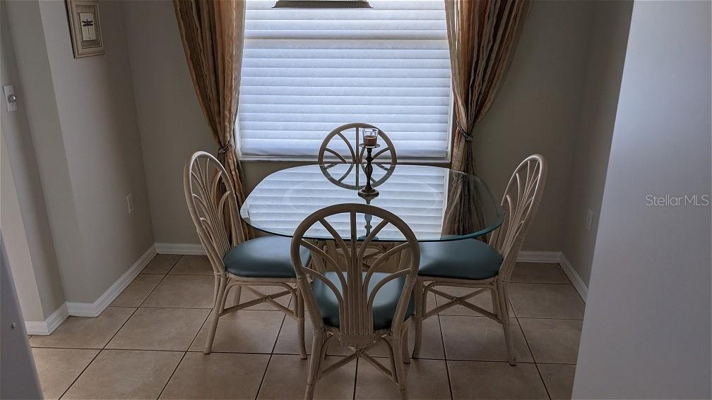 A dining area features a glass-topped table with four wicker chairs on tiled flooring — 9300 CLUBSIDE CIRCLE UNIT 1306, SARASOTA, FL