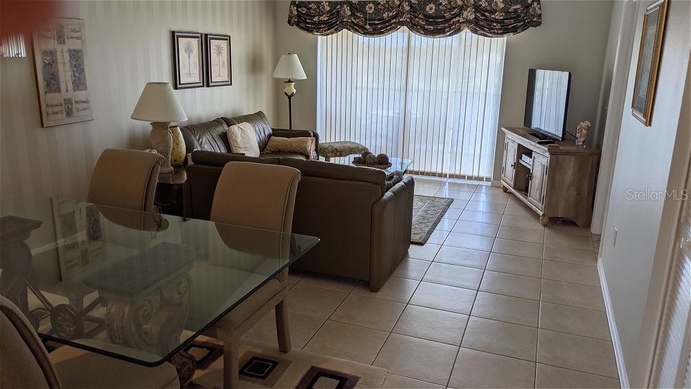 A living room and dining area with tile floors, a glass table, and a leather sofa — 9300 CLUBSIDE CIRCLE UNIT 1306, SARASOTA, FL