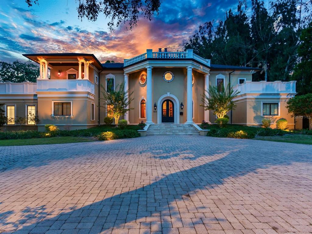A large, two-story neoclassical home with white columns and a paved circular driveway at dusk — 4623 W SAN JOSE STREET, TAMPA, FL