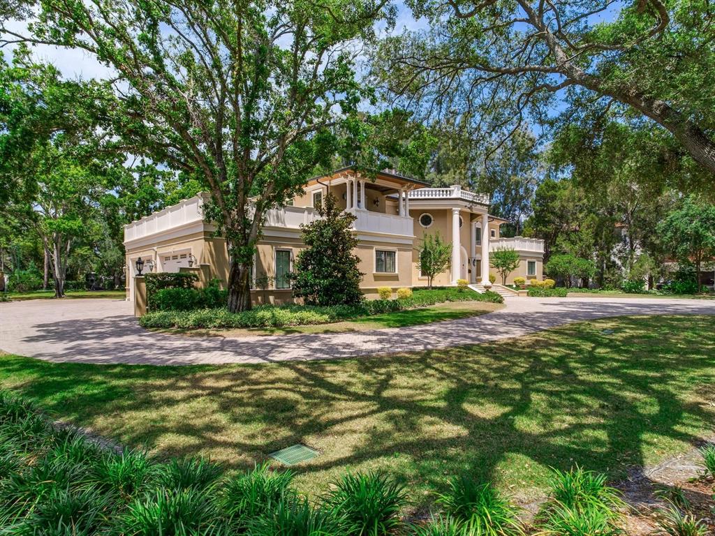 A large, two-story tan house with white trim and columns sits behind a circular driveway — 4623 W SAN JOSE STREET, TAMPA, FL