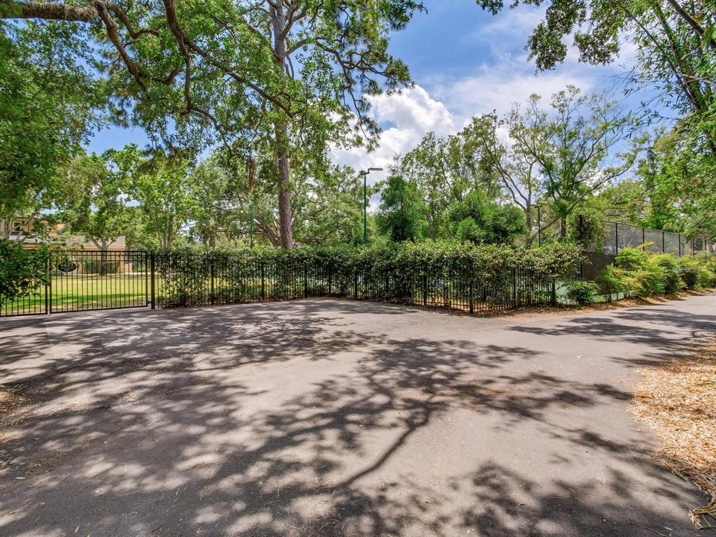 A paved driveway leads to a gated entrance surrounded by trees and a tall fence — 4623 W SAN JOSE STREET, TAMPA, FL
