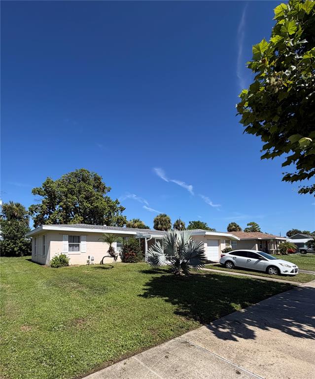A single-story house with a light-colored exterior and a white car parked in the driveway — 2353 ELKCAM BOULEVARD, PORT CHARLOTTE, FL