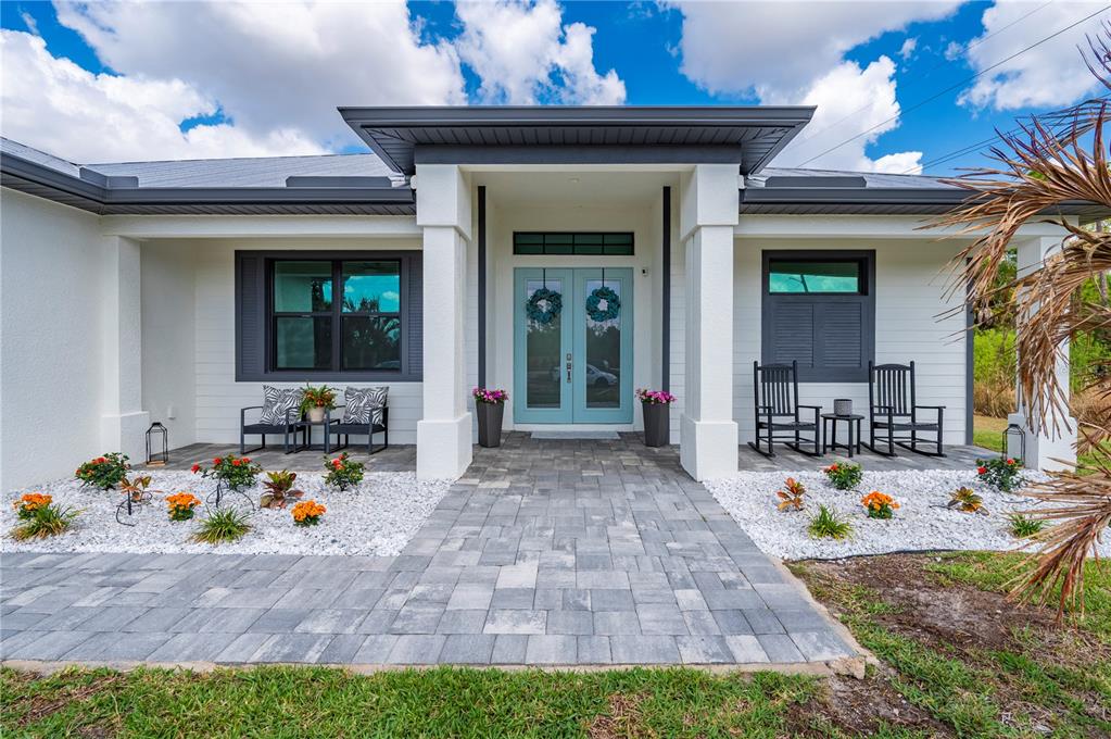 A modern house exterior features a light blue double door, white siding, and stone pavers — 4301 SOUTH ROAD, NORTH FORT MYERS, FL