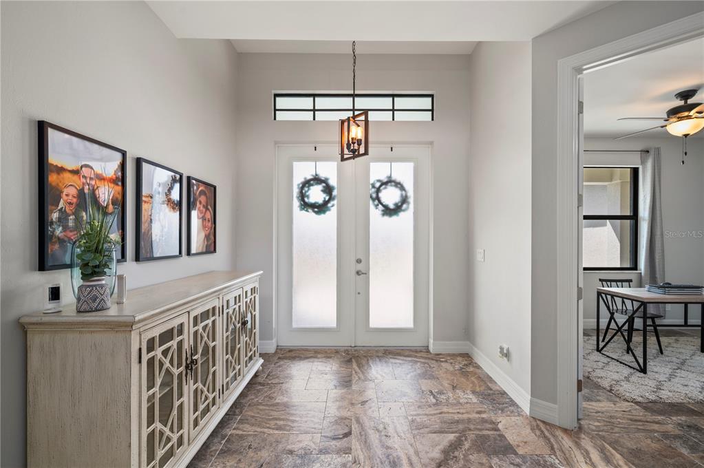 A bright entryway features a long wooden console table, tiled floors, and double glass doors — 4301 SOUTH ROAD, NORTH FORT MYERS, FL