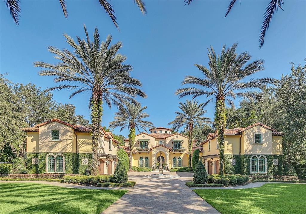 A large, two-story Mediterranean-style house with a paved driveway and tall palm trees — 1120 PRESERVE POINT DRIVE, WINTER PARK, FL