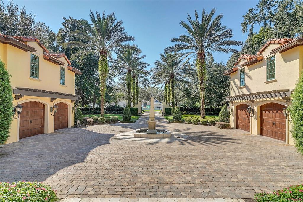 A paved courtyard features a central fountain flanked by two matching garages with palm trees — 1120 PRESERVE POINT DRIVE, WINTER PARK, FL