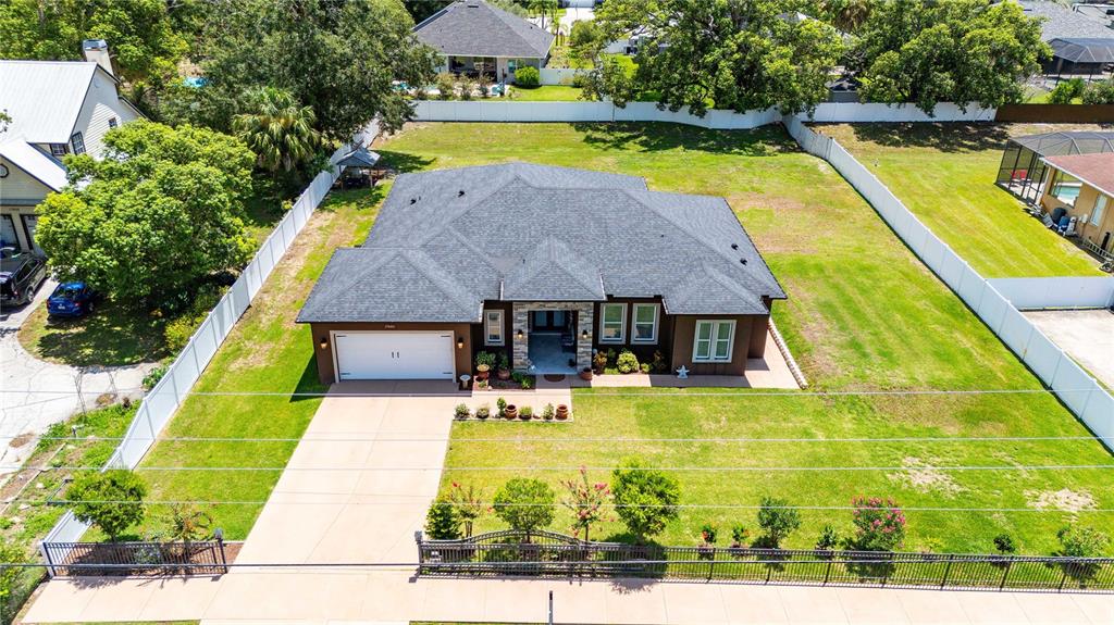 An aerial view shows a single-story house with a gray roof, white garage, and fenced yard — 17601 HANNA ROAD, LUTZ, FL