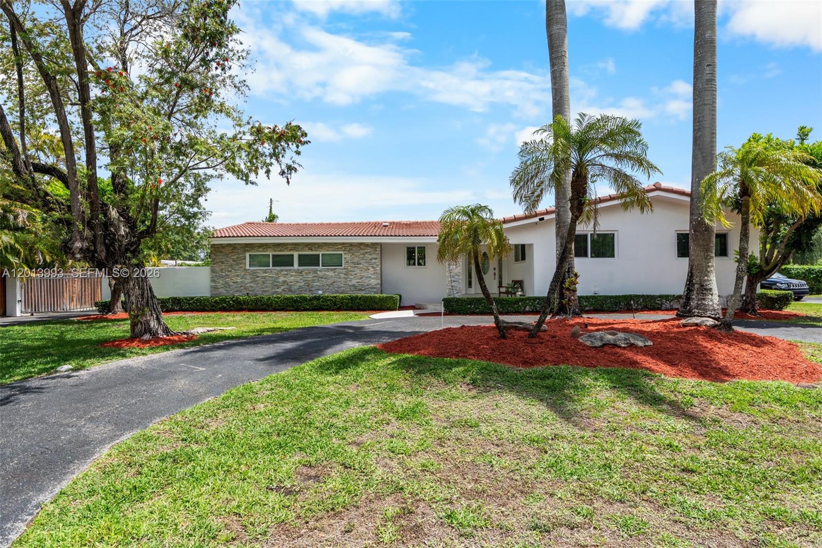 A single-story house with a stone facade, red tile roof, and palm trees in front — 12425 SW 91st Ave, Miami FL 33176, MIAMI, FL