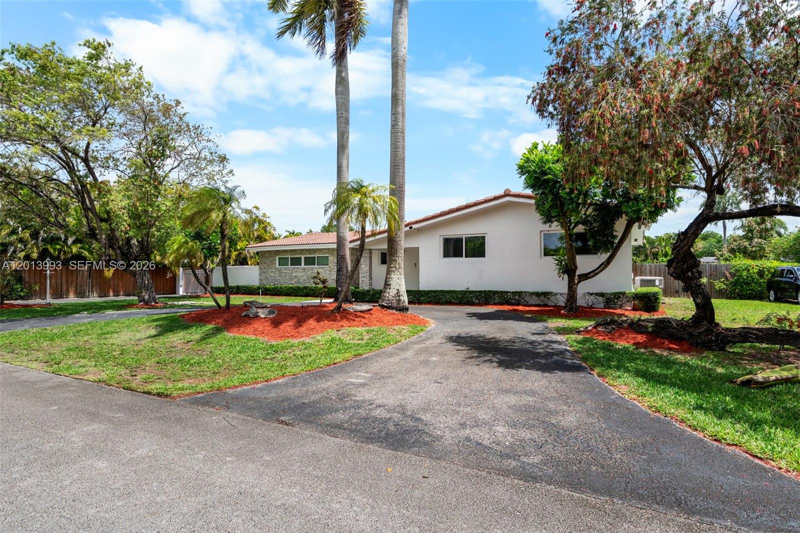 A white single-story house with a stone facade and a paved driveway surrounded by trees — 12425 SW 91st Ave, Miami FL 33176, MIAMI, FL