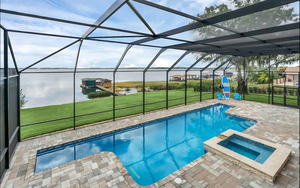 A screened-in pool and spa overlook a lake with a private dock and grassy lawn — 514 HILLSIDE DRIVE, AUBURNDALE, FL