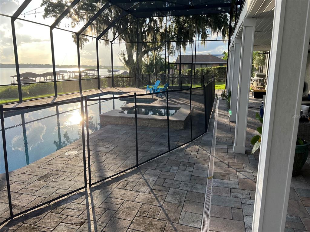 A screened-in pool and spa area features stone pavers and a view of the lake — 514 HILLSIDE DRIVE, AUBURNDALE, FL