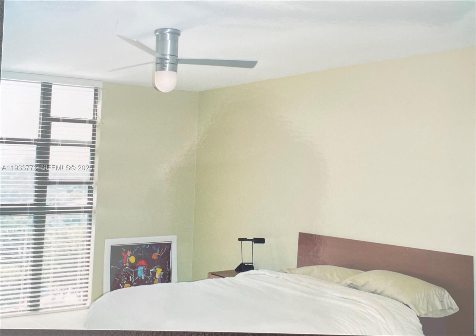 A bedroom features a bed, a ceiling fan, a window with blinds, and wall art — 1000 Quayside Ter # 806, Miami FL 33138, MIAMI, FL