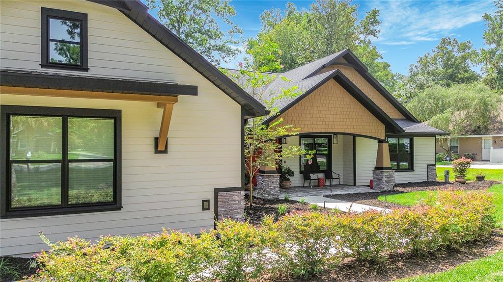 A modern house exterior features light siding, stone accents, dark trim, and a covered porch — 4977 SW 1ST AVENUE, OCALA, FL