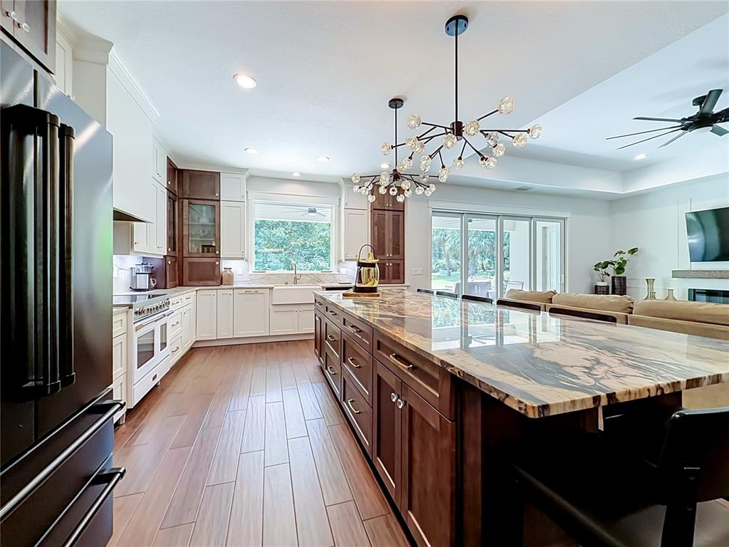 A kitchen features a large marble-topped island, dark wood cabinetry, white perimeter cabinets, and tile flooring — 4977 SW 1ST AVENUE, OCALA, FL