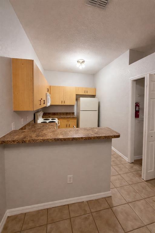 A kitchen features light wood cabinets, a laminate countertop, and a white refrigerator — 341 PORT PLEASANT DRIVE UNIT 341, KISSIMMEE, FL