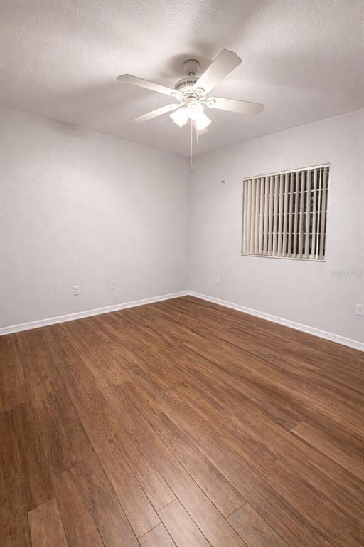 An empty room features white walls, wood-look flooring, and a ceiling fan with lights — 341 PORT PLEASANT DRIVE UNIT 341, KISSIMMEE, FL