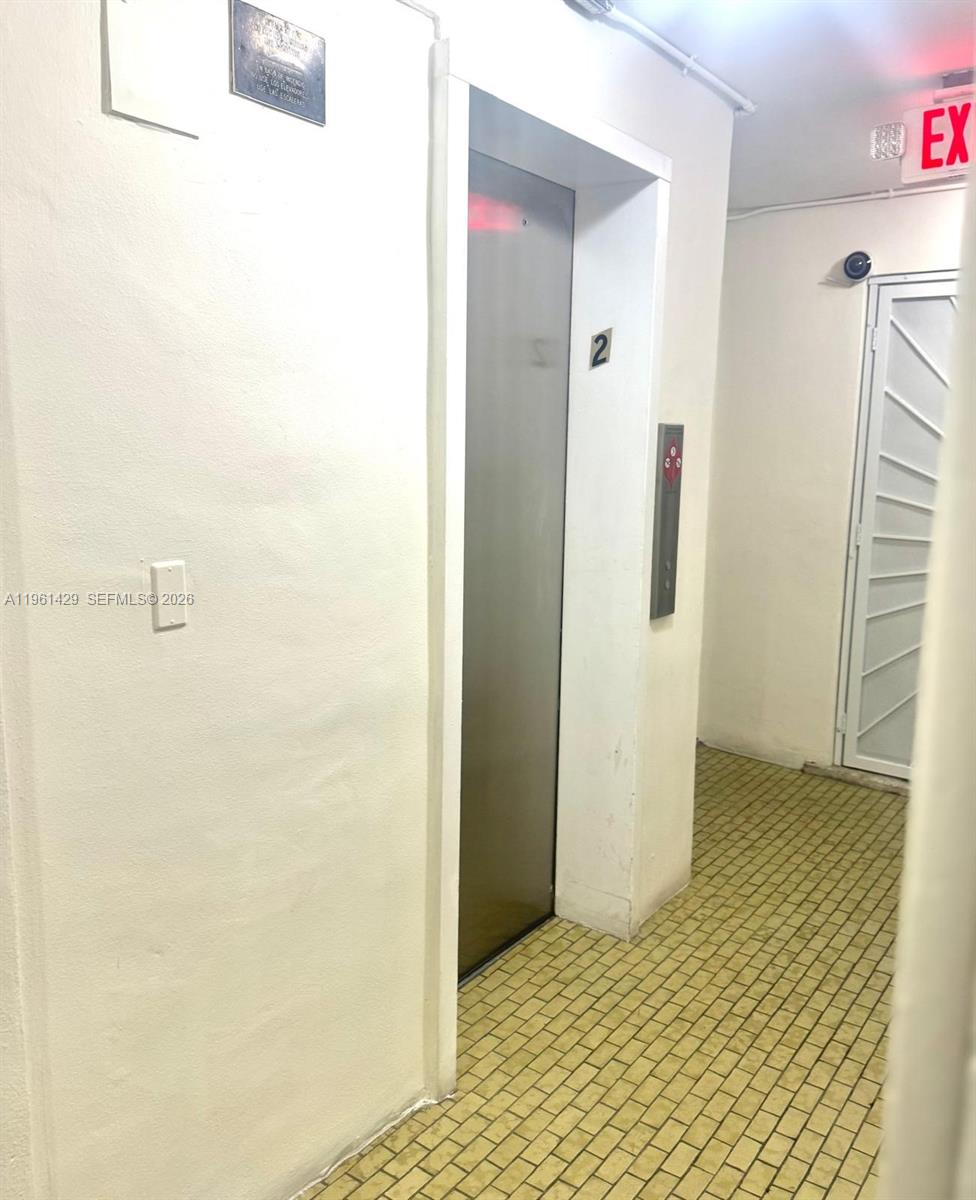 An elevator door is located in a hallway with tiled flooring and an exit sign — 755 SW 6th St # 6, Miami FL 33130, MIAMI, FL