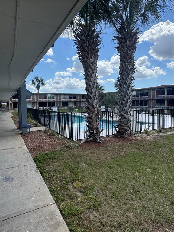 A swimming pool enclosed by a black metal fence sits between two palm trees — 43420 HIGHWAY 27 UNIT 306, DAVENPORT, FL