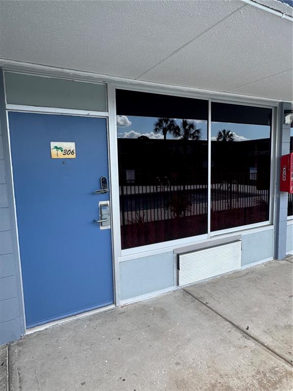 A blue door with a palm tree sign labeled 306 sits next to a large window — 43420 HIGHWAY 27 UNIT 306, DAVENPORT, FL
