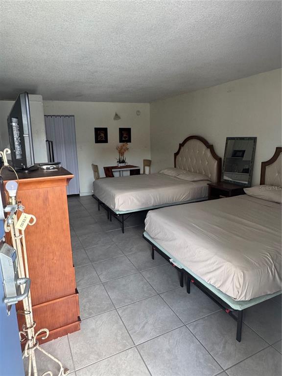 A hotel-style room features two beds, a wooden dresser, and a small dining table — 43420 HIGHWAY 27 UNIT 306, DAVENPORT, FL