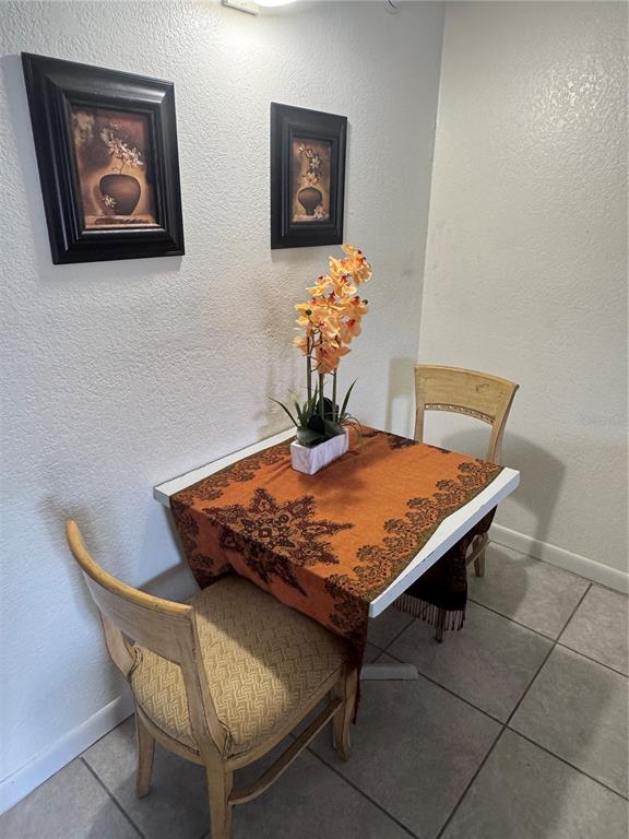 A small dining area features a square table with an orange runner, two chairs, and wall art — 43420 HIGHWAY 27 UNIT 306, DAVENPORT, FL
