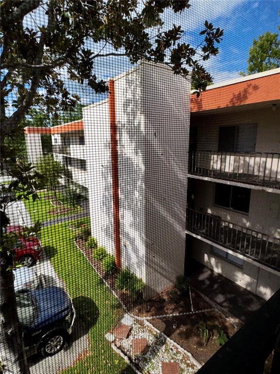An exterior view of a multi-story apartment building with balconies, seen through a window screen — 1130 N LAKE PARKER AVENUE UNIT E332, LAKELAND, FL