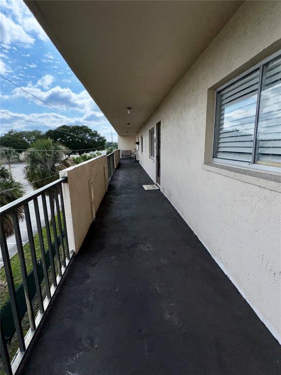 An exterior walkway with a metal railing overlooks a parking area and trees — 1130 N LAKE PARKER AVENUE UNIT E332, LAKELAND, FL