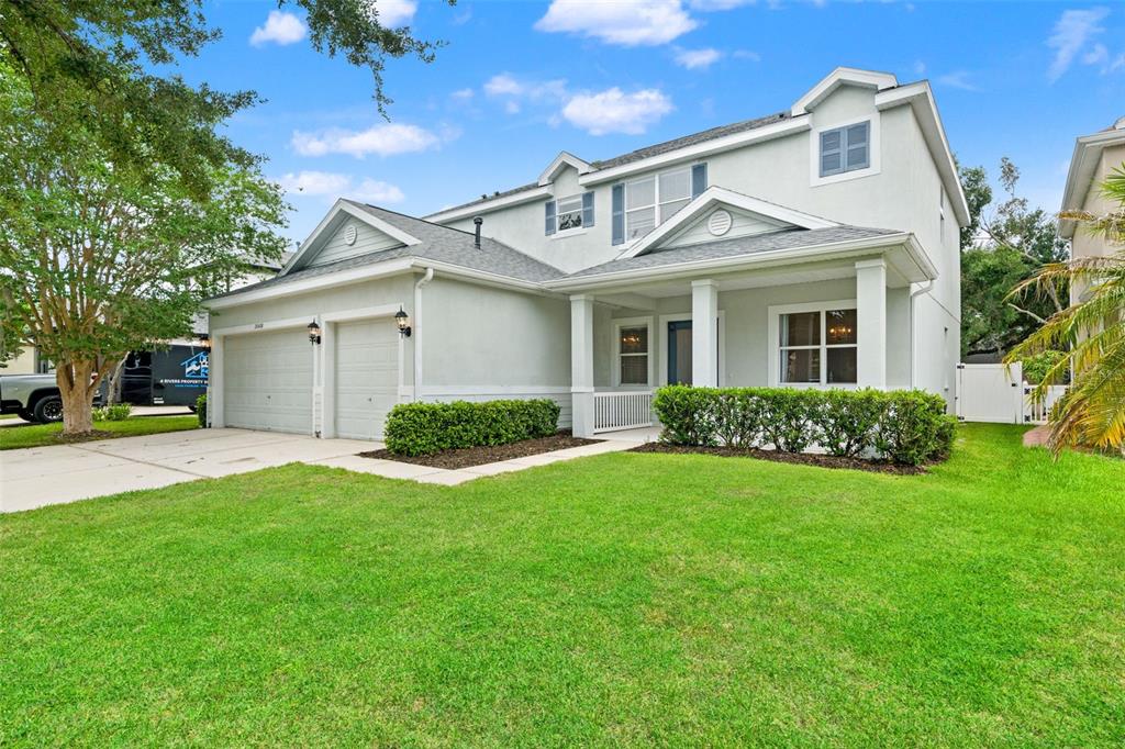 A two-story house features a two-car garage, a covered front porch, and a green lawn — 20008 BLUFF OAK BOULEVARD, TAMPA, FL