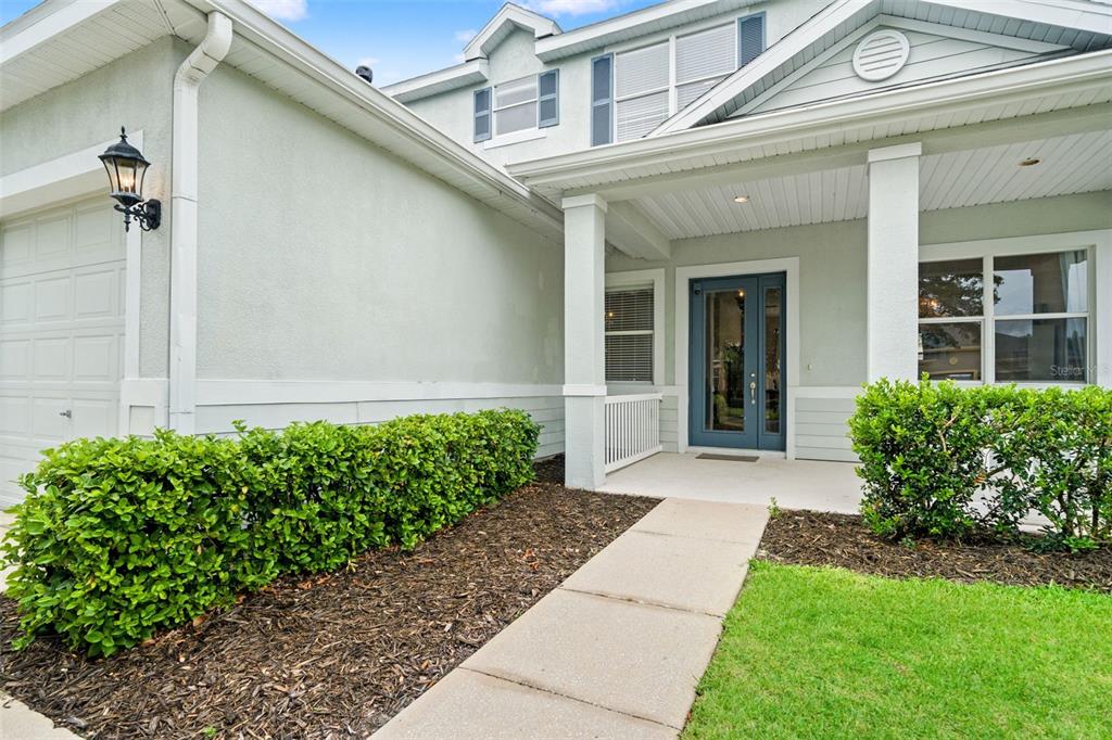 A light green house exterior features a front porch, a blue door, and landscaping — 20008 BLUFF OAK BOULEVARD, TAMPA, FL