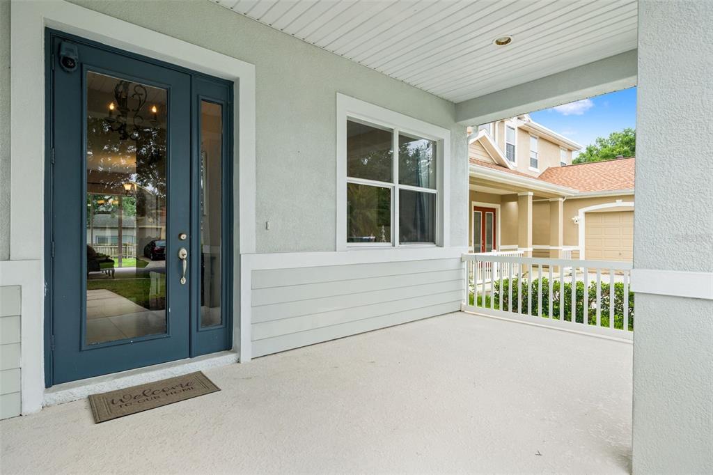 A covered front porch features a blue glass-paneled door, light siding, and a white railing — 20008 BLUFF OAK BOULEVARD, TAMPA, FL