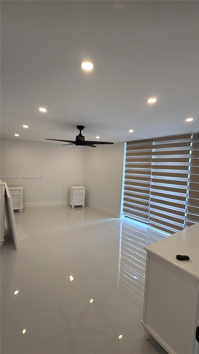 A bright, minimalist room features white tile floors, a ceiling fan, and striped window shades — 1357 NE Ocean Blvd # 311, Stuart FL 34996, STUART, FL