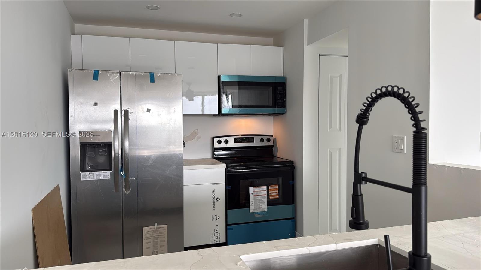 A kitchen features stainless steel appliances, white cabinets, and a black faucet over a sink — 1357 NE Ocean Blvd # 311, Stuart FL 34996, STUART, FL